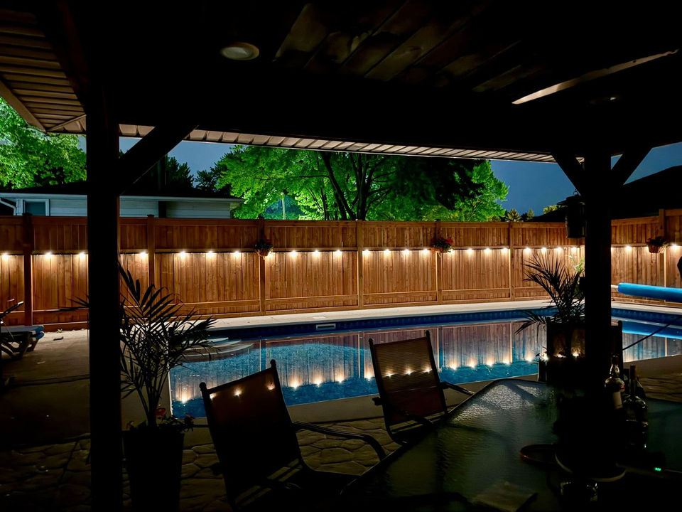 Warm white pot lights surrounding a backyard and swimming pool