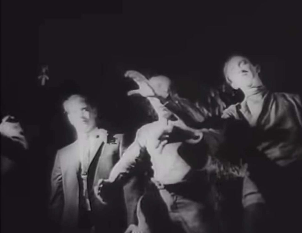 A group of zombies reach for a camera