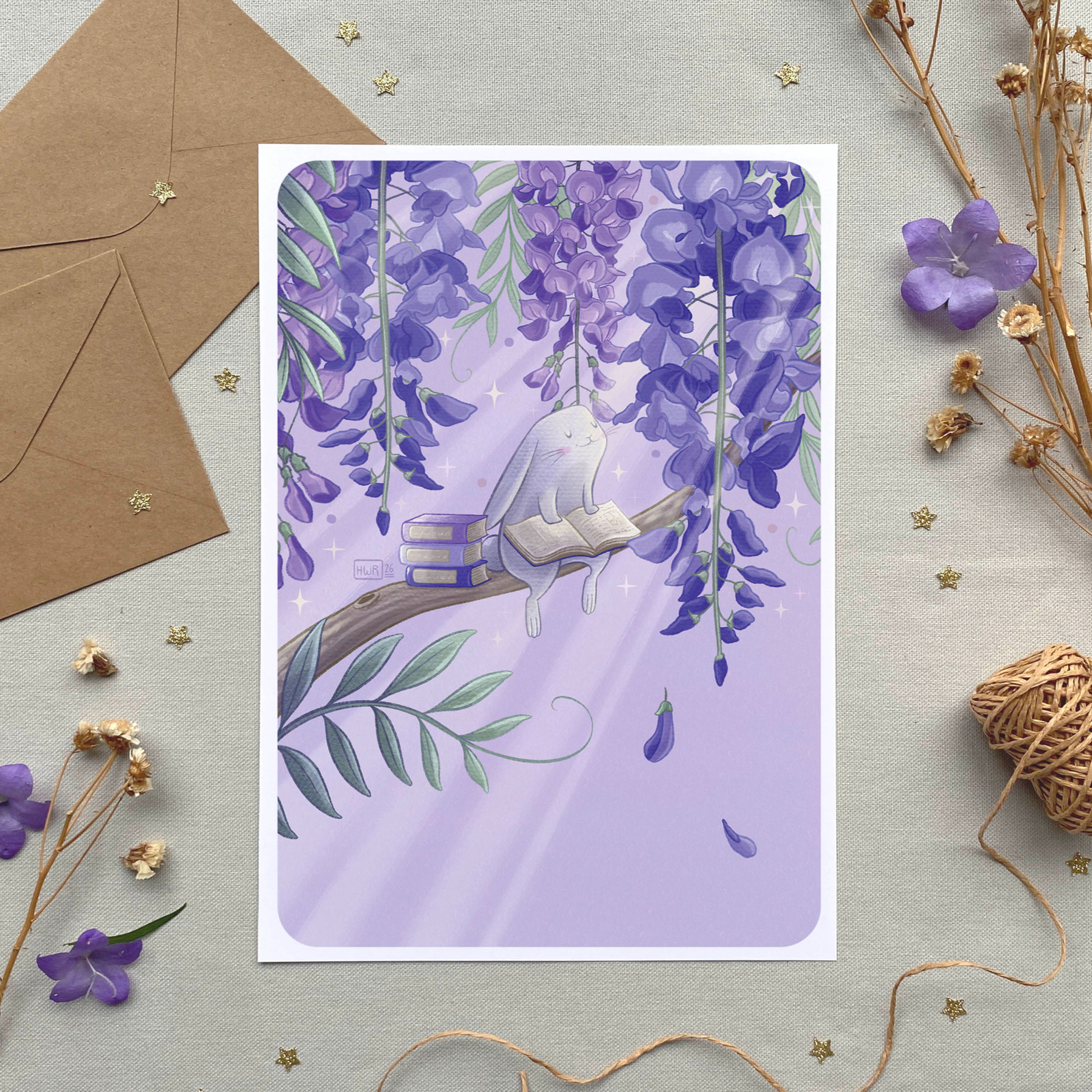 Petit lapin blanc sur branche de glycine en illustration A4, décor printanier avec fleurs et enveloppes kraft, vue de haut.
