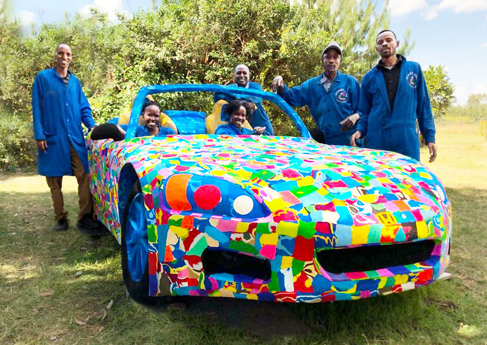 Ocean Sole’s upcycled car sculpture, with two women seated in the vehicle and four men standing alongside, all artisans who helped create the piece from thousands of discarded flip‑flops.