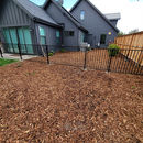 Wrought iron fence in yard with bark and a view of the house