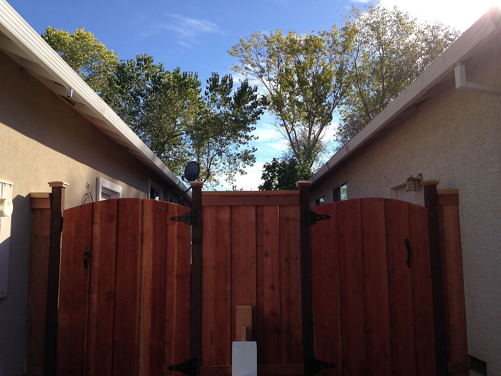 Double gate with tall post and post cap with small section in between redwood fence installed in Ros
