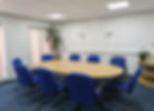 Oblong conference table with oak wood and eight blue coloured business chairs.