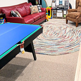 Professionally organized multi-age playroom featuring designated zones for preschool play and preteen lounging, using labeled storage and clear floor space to maximize basement functionality.