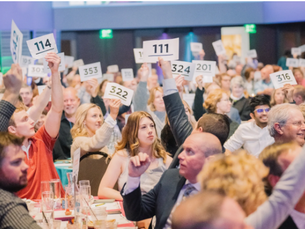 room full of people holding up white pieces of paper with numbers on them