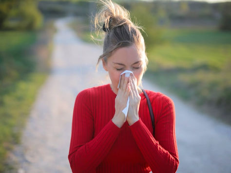 Mujer con alergia primaveral estornudando al aire libre por el polen