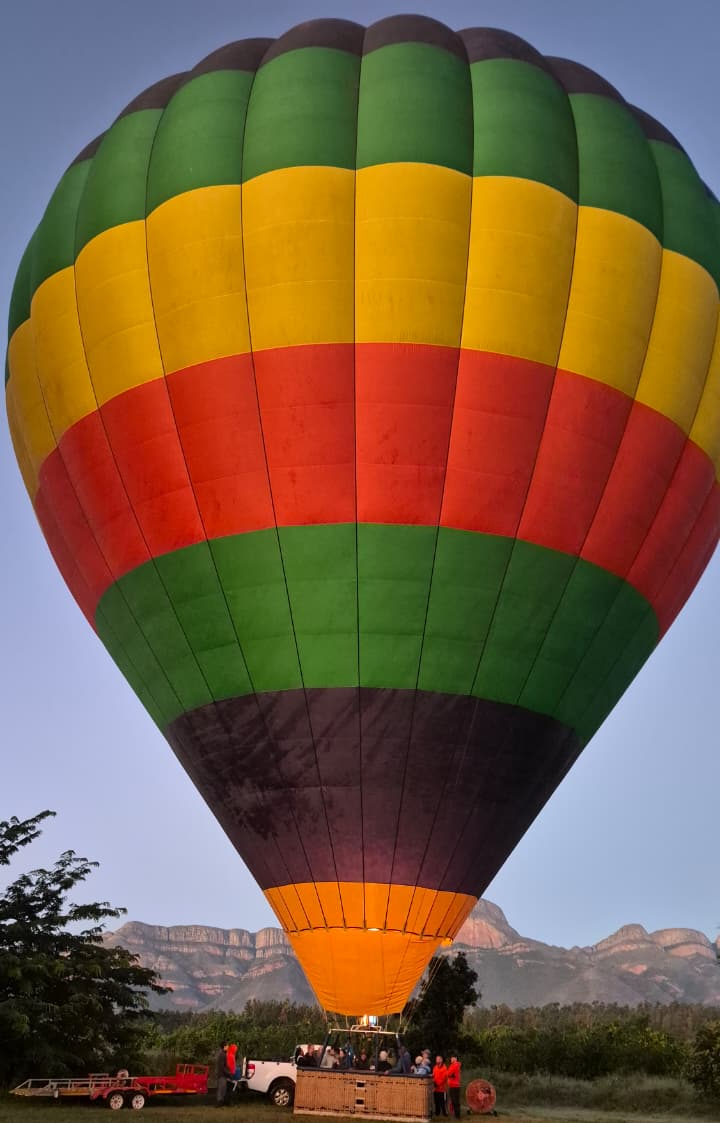 A hot air balloon floating gracefully over the golden African savannah at dawn.