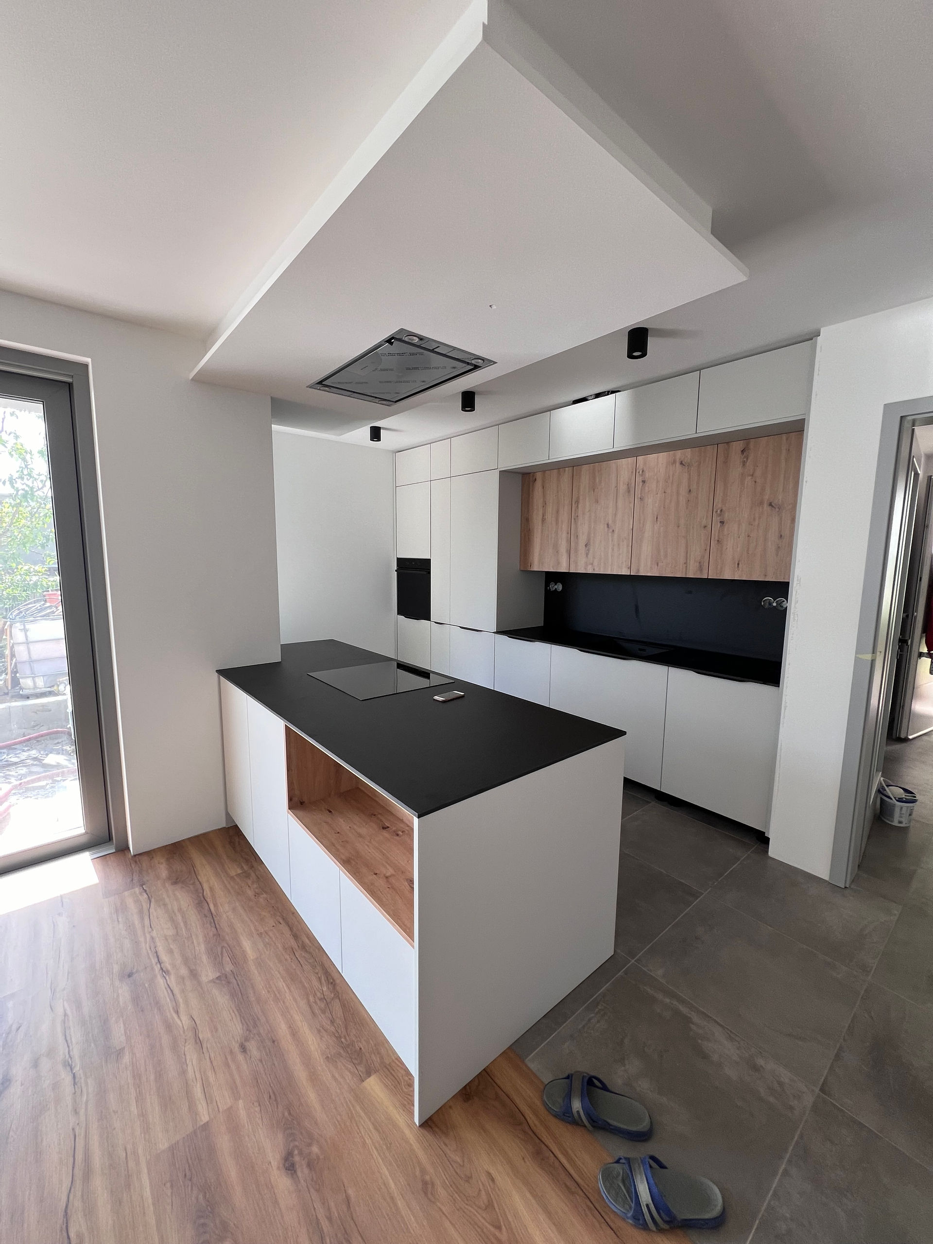 Dokončená kuchyňská linka s ostrůvkem, černou deskou a vestavěnými spotřebiči