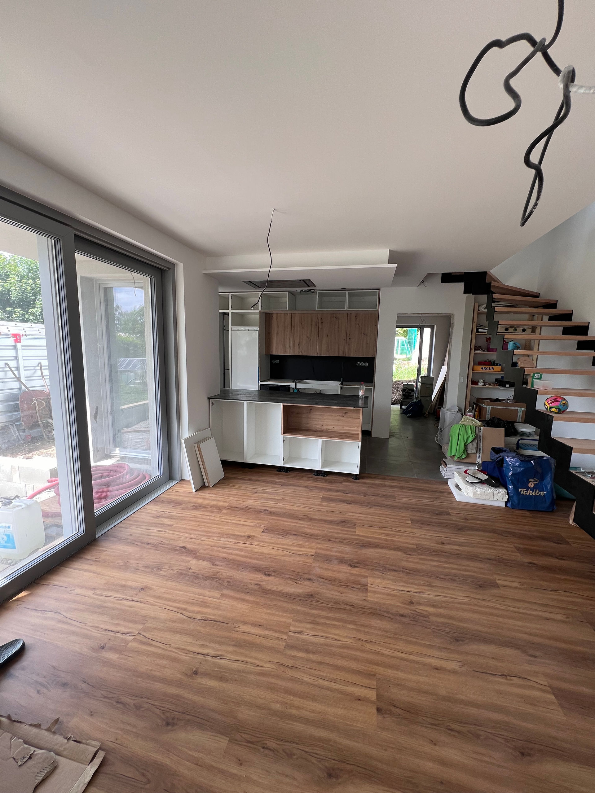 Montáž bílé kuchyňské linky s ostrůvkem a dřevěným dekorem ve světlém interiéru