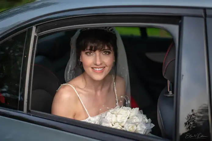A bride in her wedding dress with a bouquette arrives at the Church