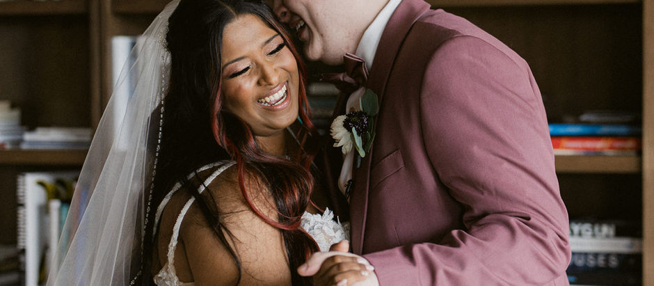 A bride and a groom laughing with each other on their wedding day.