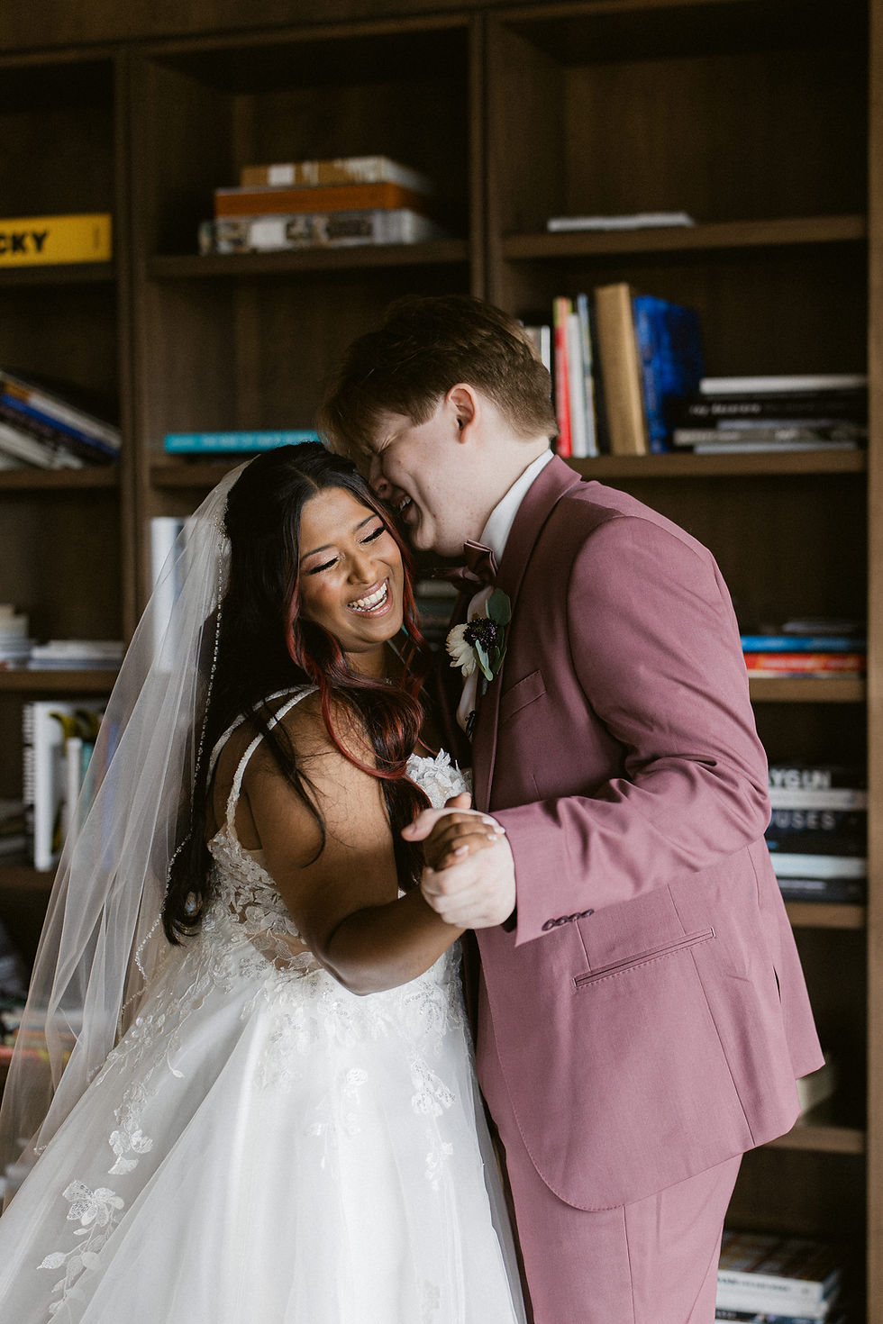 A bride and a groom laughing with each other on their wedding day.