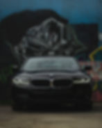 Black BMW car parked in front of graffiti wall mural.