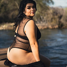 Kings River boudoir photography – woman in sheer black lingerie posing by water’s edge during outdoor session.