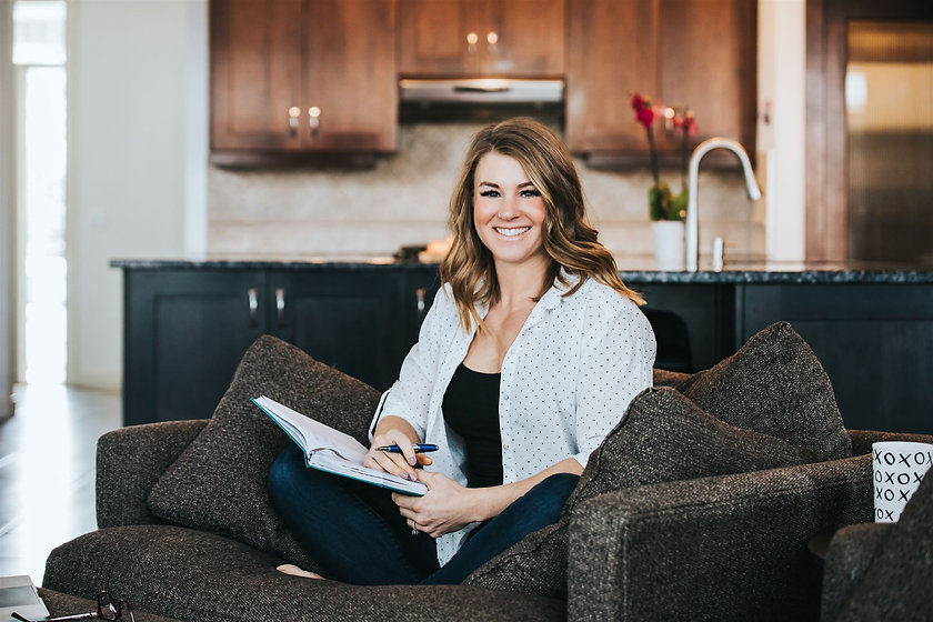 Woman sitting on a couch with a notebook smiling warmly