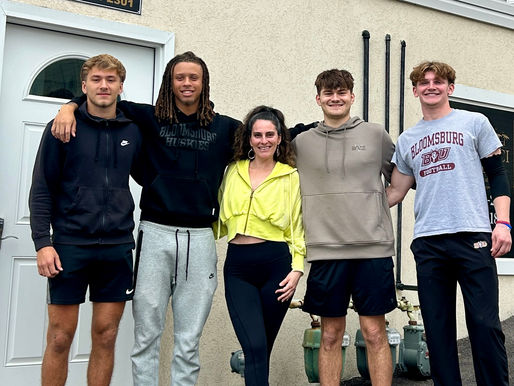 woman with four college athletes smiling for a photo