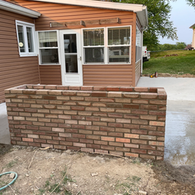 brick half-wall on perimeter of back patio