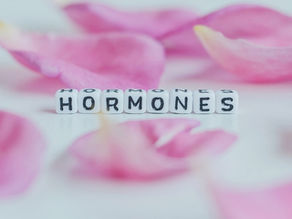Letter beads spelling out the word hormones, surrounded by pink flower petals