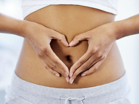 Love your gut. Image shows a woman making a heart symbol with her hands in front of her stomach.