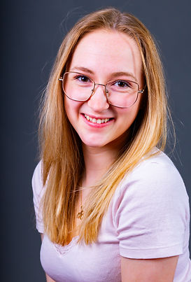 Lächelnde Frau mit Brille bei einem Portraitshooting vor dunklem Studiohintergrund