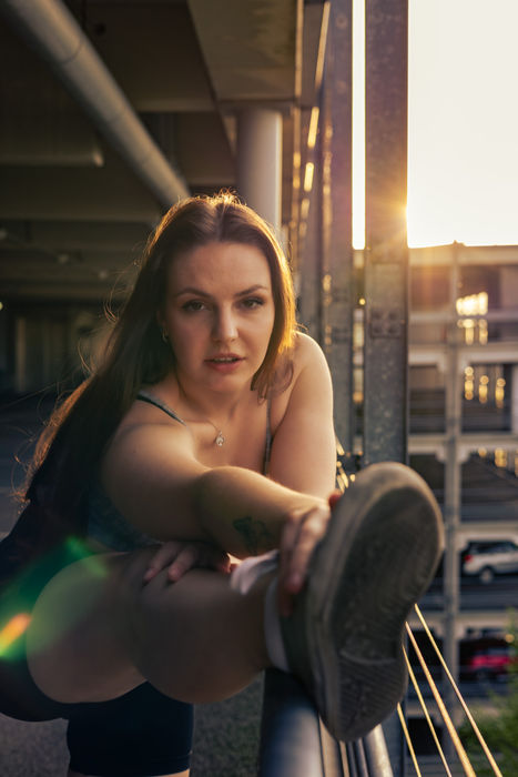 Frau sitzt lässig auf einem Stuhl in einer industriellen Indoor-Location bei einem Portrait-Shooting.