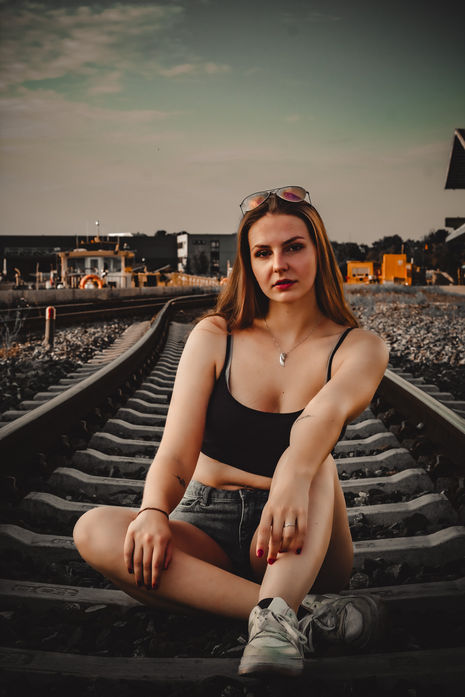 Frau sitzt auf Bahngleisen bei einem urbanen Portrait-Shooting im Freien.