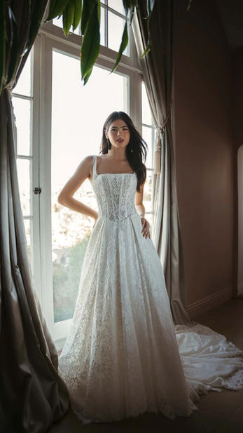 SQUARE NECKLINE ALLOVER LACE A-LINE WEDDING GOWN WITH CORSET BODICE

A romantic fusion of classic texture and contemporary structure, Style SY8344 is enveloped in breathtaking lace from its modern neckline to the edge of its sweeping train. The bodice features a fashionable square neckline and visible corset boning, offering a sophisticated, architectural fit that defines the natural waist. This wedding gown provides versatility for the individual aesthetic, offered with both a lined and unlined bodice option to control the level of sheerness. Flowing into a graceful A-line silhouette, the intricate lace patterns create an organic, multidimensional look that remains elegantly unadorned by beading. The back is finished with a streamlined zipper closure and classic fabric-covered buttons, ensuring a polished and timeless bridal finish. This gown is also available in plus sizes.