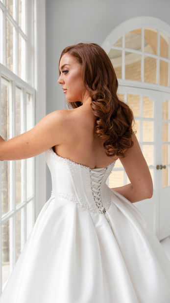 Embrace modern indulgence in Mystique. This stunning ballgown features a structured pearl-embellished corset bodice and a voluminous, sweeping mikado skirt for a look of pure luxury.