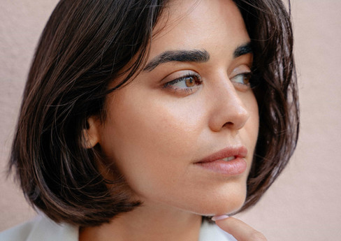 das braunhaarige Model Hila schaut nachdenklich zur Seite und hat einen Finger am Kinn