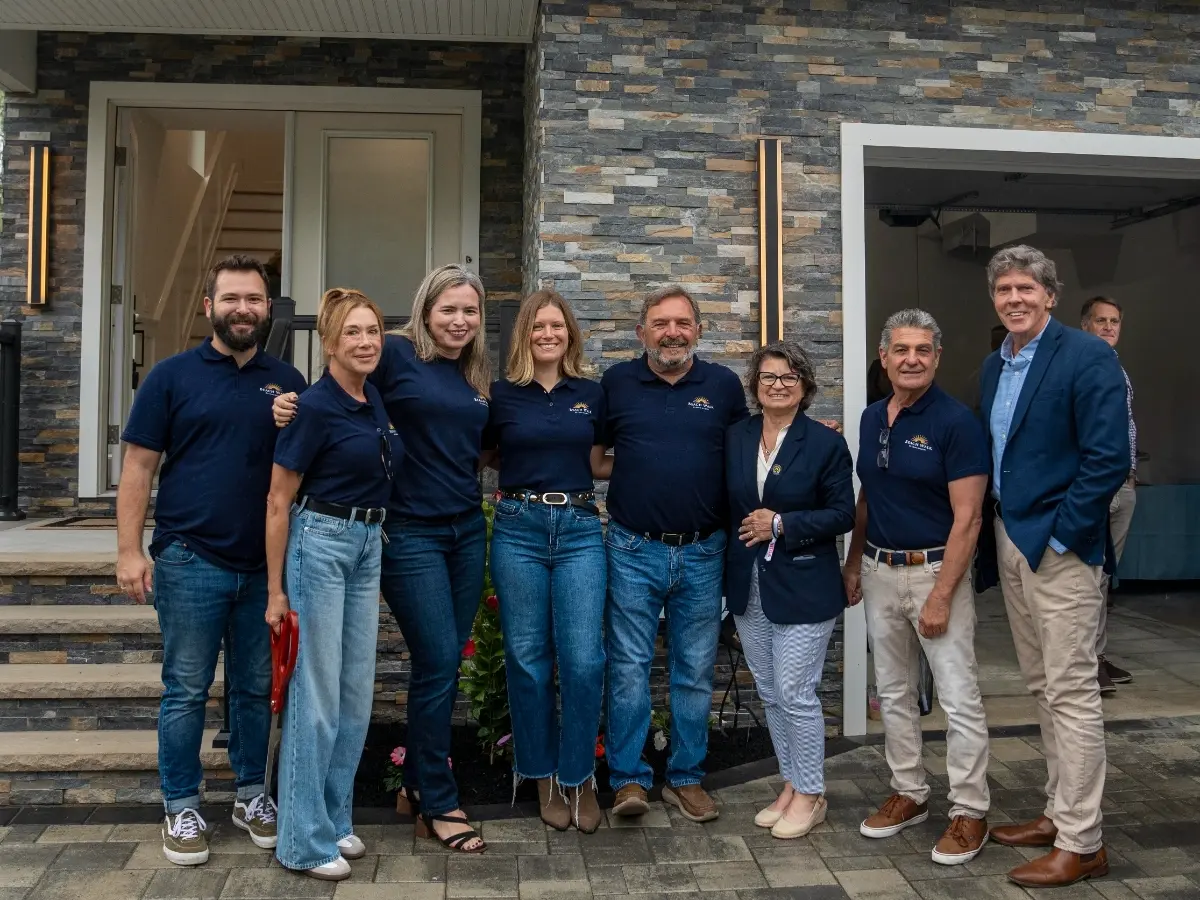 Group photo at the BeachWalk ribbon cutting with Long Branch Mayor John Pallone, DeLynn and Gary Schecher, and Cross Builders employees gathered in front of the new development