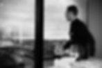 Mood-Detail in der Elbphilharmonie Hamburg: Ein Angestellter steht unscharf vor einem Fenster und blickt Richtung Hafen, im Vordergrund Catering und ein Wasserglas
