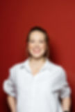 Christina Schäfers mit einem strahlenden Lachen vor einer roten Wand