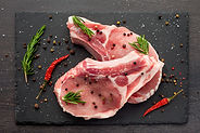 fresh raw meat with spices and rosemary and red pepper on black slate, on dark background,