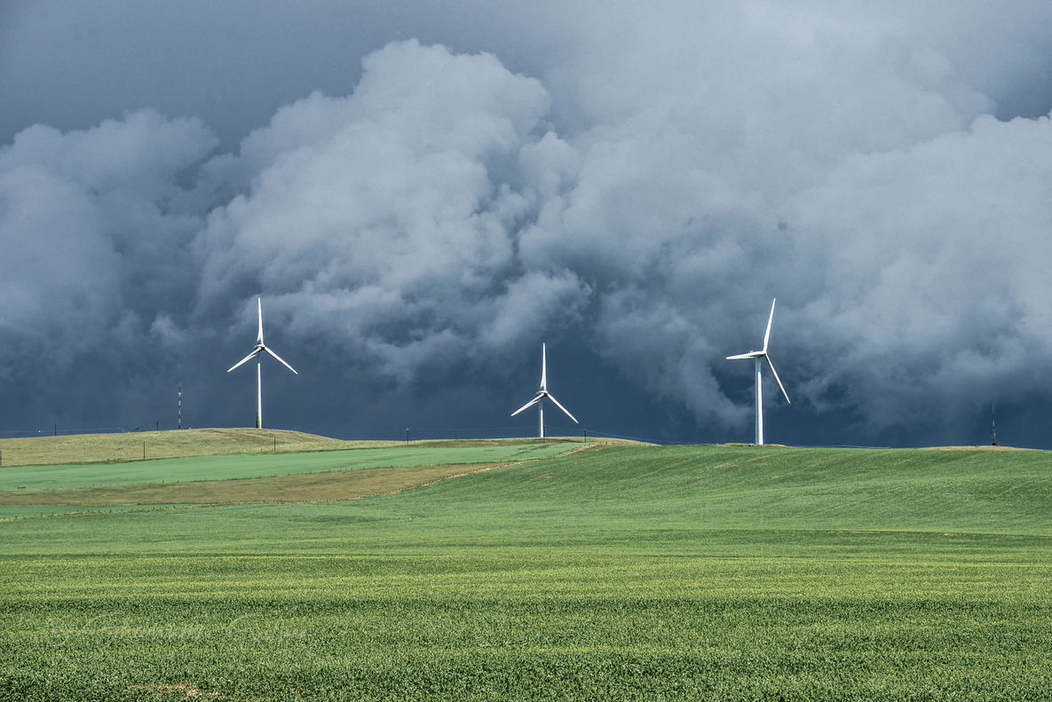 Wind turbines standing against the backdrop of an approaching storm with dramatic and threatening cumulo-nimbus