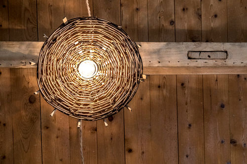 Rénovation maison de famille en Bourgogne par AMCD, architecte d'intérieur. Détail luminaire en osier et goulotte sur mesure en bois cachée dans la poutre. 