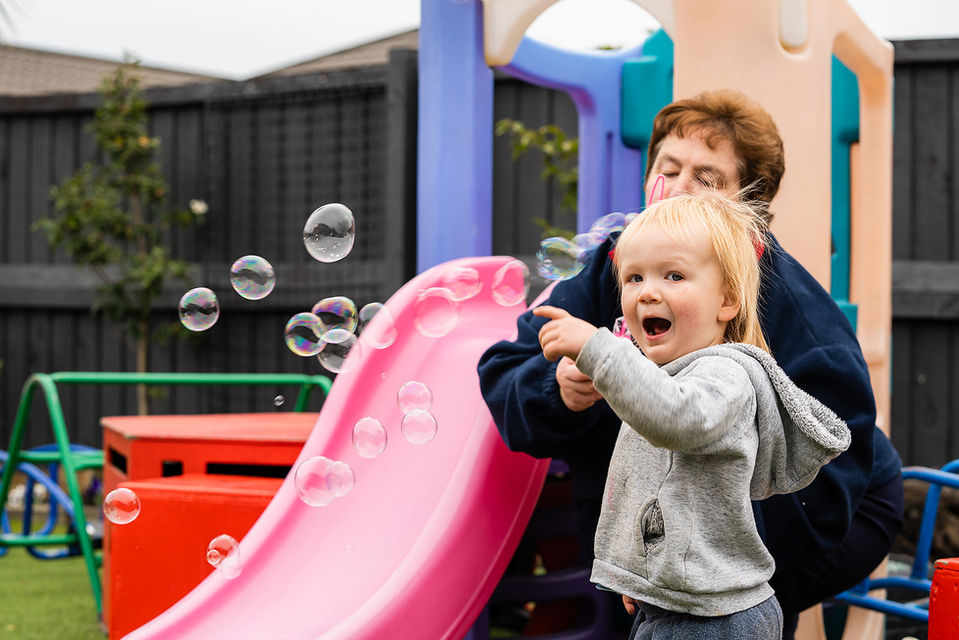 Blowing bubbles by the slide at the Spreydon Christian creche