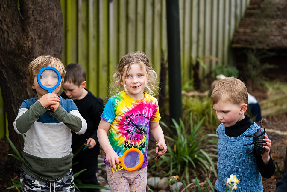 Playing with toy magnifying glasses in the garden at creche in Spreydon