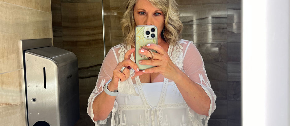 A woman with a phone looking into a mirror.