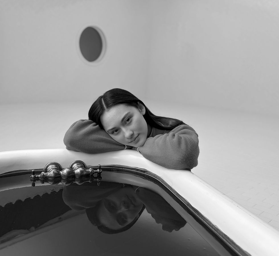 Black-and-white still from Osgood Perkins’ The Young People, showing Lola Tung seated on a blood-filled bathtub.