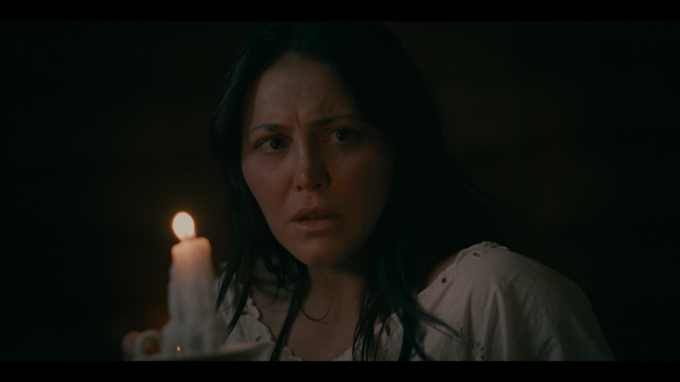 A woman stands in a dusty western town looking distressed.