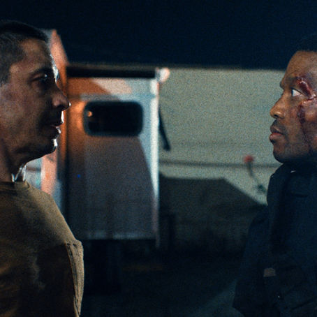 RJ Cyler in Night Patrol standing under flickering streetlights in Los Angeles, blending horror and realism.