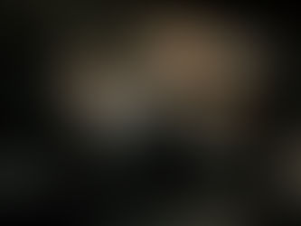 A hippopotamus surfaces in dark swamp water near a boat.