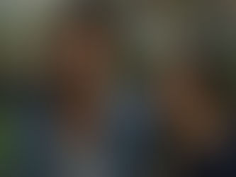 A man stares at an eerie older woman in a dim room.