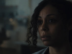 A woman sits in a dark room connected to a sci-fi device.