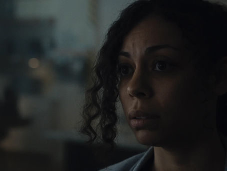 A woman sits in a dark room connected to a sci-fi device.