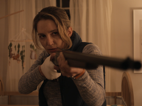 A tense couple stands over a child in a dimly lit room, suggesting something is wrong.