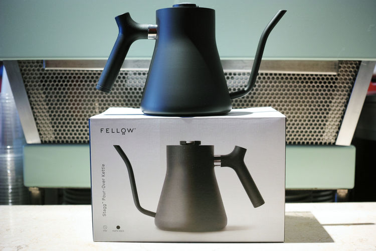 Black goose next kettle sitting on it's retail box that has it's image and text of Fellow Stagg Pour over Kettle.