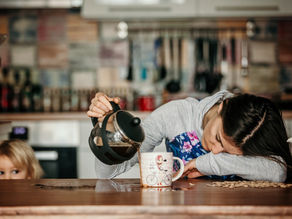A lady falling asleep while pouring coffee with a child watching nearby