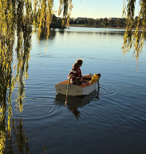 Pip, the founder of Mountain Boats sculling in an 8' Pram dinghy on Lake Burley Griffin with his son