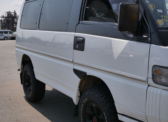 Side view of a 1994 Mitsubishi Delica 4WD diesel van with lifted aftermarket suspension, rugged off-road stance, and white two-tone paint – ideal for overlanding or adventure travel.